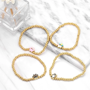 Detailed view of beaded gold bracelets with enamel animal paw and panda pendants