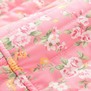 Gros plan sur un tissu matelassé à fleurs roses avec surpiqûres blanches pour vêtements
