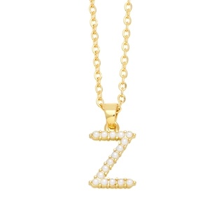 Detailed close-up of golden necklace pendant with letter Z and small pearls inlay