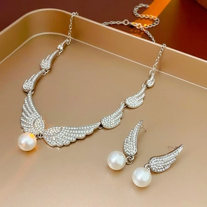 Macro view of silver wing earrings and necklace set with sparkling crystals and pearls