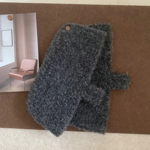 Detailed texture of grey knitted gloves pinned on cork board with natural lighting