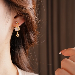Close-up of a model wearing elegant gold-plated flower tassel earrings with zircons