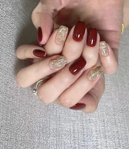 Detail of square-round press-on nails in glossy deep wine red and champagne gold glitter