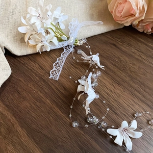 Detail of white fabric flower hair clip with lace ribbons and lustrous pearls