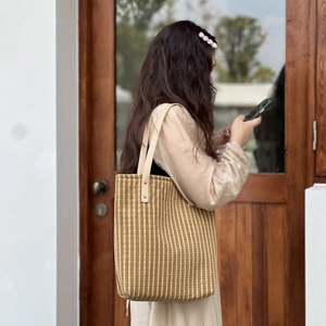 Detail view of a vertical striped cotton tote bag with sturdy beige leather shoulder handles