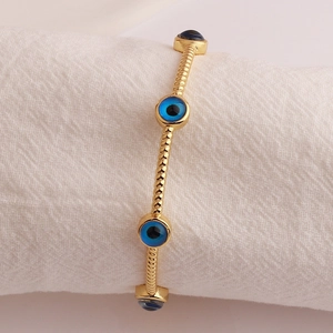 Gold-plated spiral evil eye cuff bracelet featuring blue glass charms for women