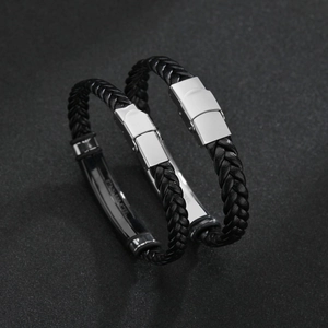 Minimalist braided leather bracelet with stainless steel clasp on a dark textured surface