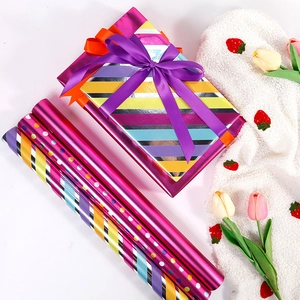 Colorful striped and polka dot gift wrapping paper rolls with a decorated gift box