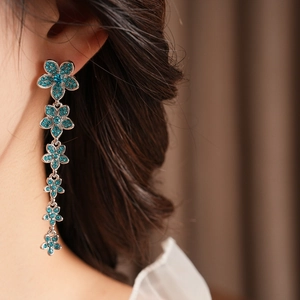 Détail de boucles d'oreilles pendantes à fleurs en zircon sarcelle sur un mannequin