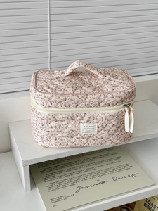 Macro detail of quilted corduroy makeup bag featuring floral patterns and dual zippers
