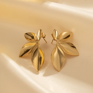 Elegant gold leaf-shaped stud earrings made of stainless steel on champagne silk