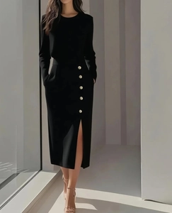 Detail of elegant black long sleeve dress with side slit and decorative metal buttons