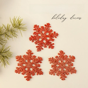 Drei rote glitzernde Weihnachts-Schneeflocken-Anhänger mit Tannenzweig auf beigem Grund