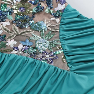 Detail of teal halter dress showing sequin embroidery and pleated mesh fabric texture