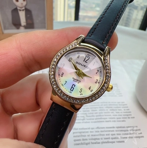Detailed close-up of a stylish quartz watch with a gold diamond bezel and black leather strap