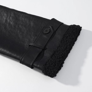 Detail of the black leather sleeve cuff featuring plush lining and a decorative buttoned strap