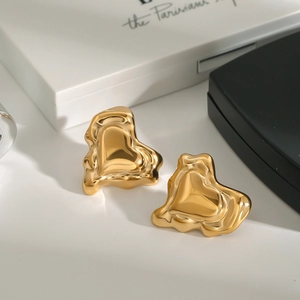 Détail des boucles d'oreilles cœur dorées avec finition polie sur emballage cadeau