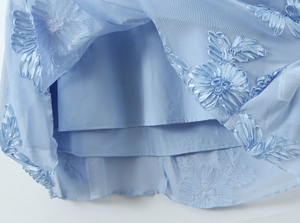 Détail du tissu en maille bleu clair avec fleurs en ruban 3D et doublure