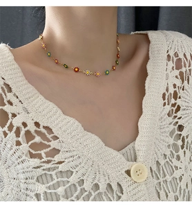 Close-up of colorful beaded daisy flower necklace with gold chain on model neck