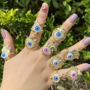 Detail of 18K gold ring set featuring heart, crescent, and evil eye motifs on a model