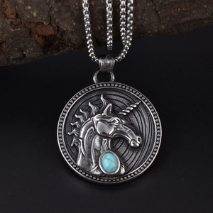 Detail of vintage silver unicorn pendant with turquoise gemstone on wood background