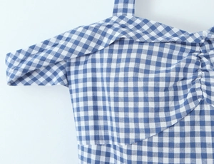 Detailansicht eines blau-weiß karierten Kleides mit Neckholder und plissierten Details