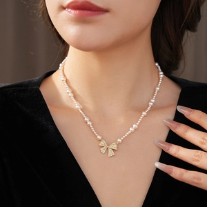 Close-up of pearl bow necklace with golden zircon pendant on a fashion model