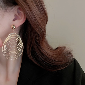 Close-up of model wearing gold layered hoop earrings with minimalist black suit