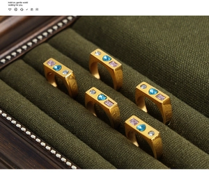 Detailed view of gold plated titanium rings with heart-shaped gems in green velvet box