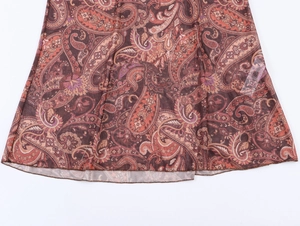 Détail de l'ourlet de robe à motif paisley avec des motifs en maille marron et orange