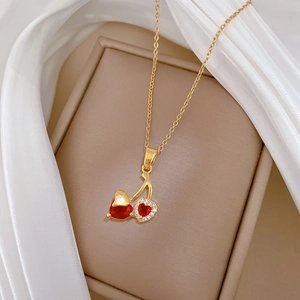 Macro view of gold cherry necklace pendant with red heart gem and white zirconia crystals