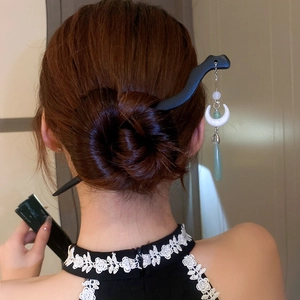 Detail of wooden hair stick with elegant jade-like flower tassels on a classic bun