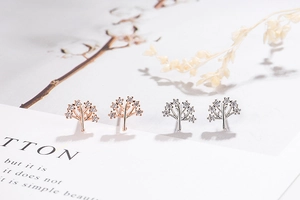 Detail of rose gold and silver tree of life stud earrings with sparkling cubic zirconia