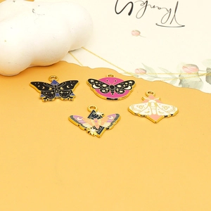 Detailed macro view of moth-shaped enamel charms with celestial moon and star patterns