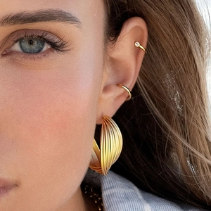 Golden layered geometric hoop earrings and ear cuffs on female model in stylish pose