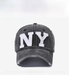 Detail of NY logo embroidery on washed dark grey distressed cotton baseball cap