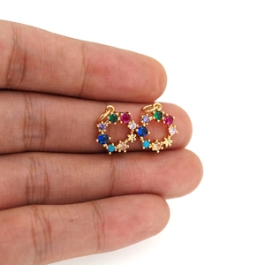 Vue macro de mini pendentifs couronne en zircon plaqués or 18 carats sur les doigts