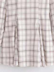 Detailansicht des grau-weißen Karostoffs mit sichtbaren Nähten und Textur am Kleid