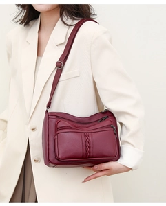 Model wearing dark wine red soft leather crossbody bag with multiple zip pockets