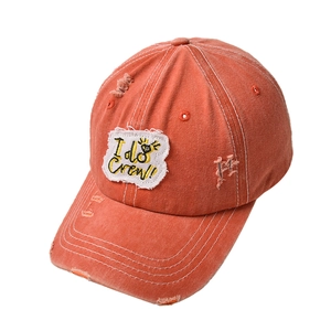 Macro detail of distressed orange baseball cap with embroidered I do Crew patch