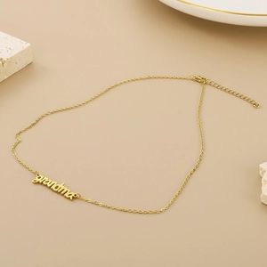 Detail of a golden Grandma pendant necklace displayed on a textured stone for Mother's Day