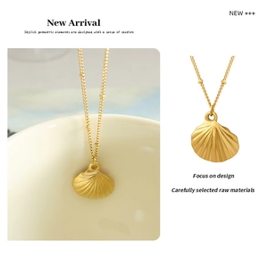 Close-up of gold satellite chain and scallop shell pendant with textured details
