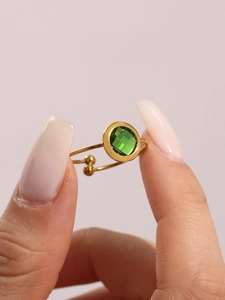 Detail eines minimalistischen vergoldeten Rings mit einem grünen böhmischen Glasstein