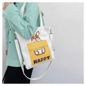 Detail of white canvas tote with yellow Corgi pocket and adjustable strap on model