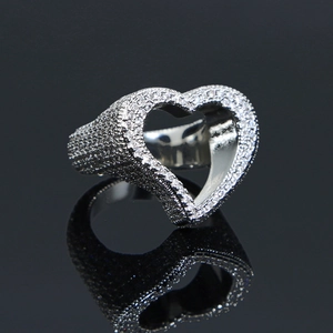 Macro view of iced-out silver heart ring with pave-set cubic zirconia on black mirror