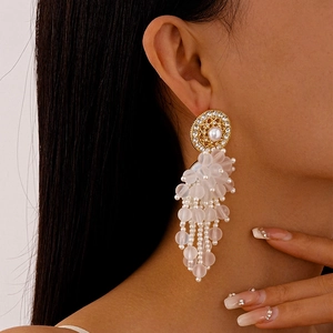 Gros plan de boucles d'oreilles à pampilles avec perles et strass portées par un mannequin