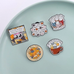 Set of five creative cartoon cat enamel pins in various shapes on a pastel round plate
