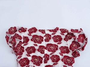 Detail eines eleganten weißen Kleides mit roten Blumenmustern und Rückenreißverschluss