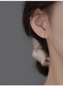 Close-up of elegant gold tulip earring with crystal-inlaid leaf on a female model