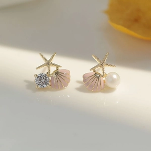 Detailansicht asymmetrischer Ohrstecker mit Seestern und rosa Muschel im Meeresdesign